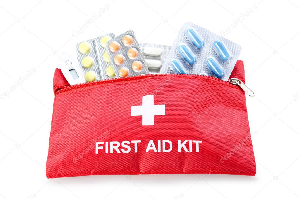 First aid kit with pills in blisters and thermometer isolated on white background