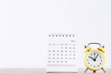 Beyaz arkaplanda sarı alarm saati olan takvim sayfası