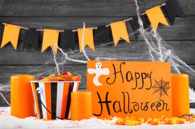 Mutlu Cadılar Bayramı 'nı kovada şekerler ve ahşap arka planda mumlarla kutlayın.