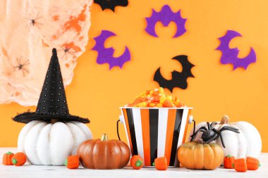 Cadılar Bayramı balkabakları, şekerler, örümcek ve kağıt yarasalar turuncu arka planda