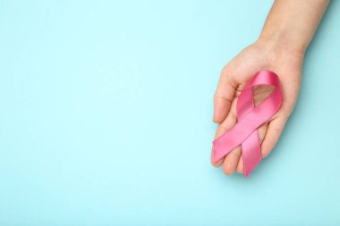 Göğüs kanseri konsepti. Mavi arka planda pembe kurdeleli bir kadın.