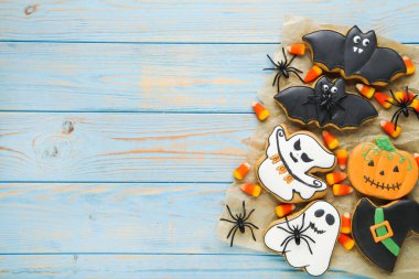 Cadılar Bayramı zencefilli kurabiyeler ve mavi ahşap masada örümcekler.