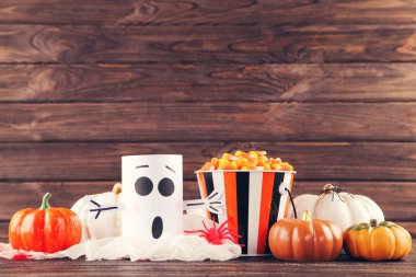 Hayaletli Cadılar Bayramı balkabakları, kahverengi ahşap arka planda şekerli kova