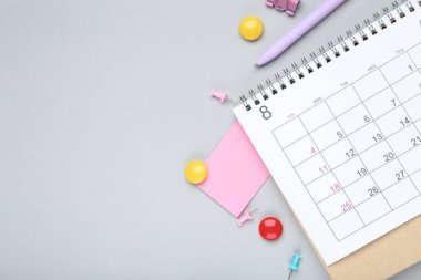 Gri arkaplanda yapışkan notlu ve kalemli takvim sayfası