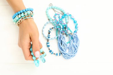 Beyaz ahşap arka planda mavi bilezikli bir kadın.