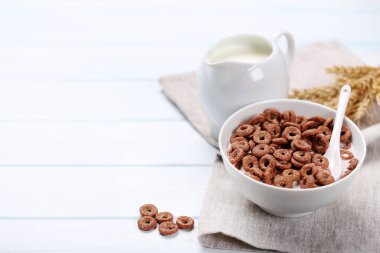 Çikolatalı mısır gevreği kasede süt ve peçeteyle ahşap masada.