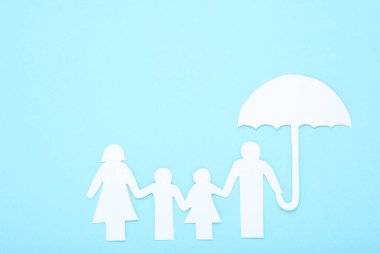 Mavi arka planda şemsiyesi olan kağıt aile figürleri