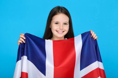 Mavi arka planda İngiliz bayrağı tutan genç kız