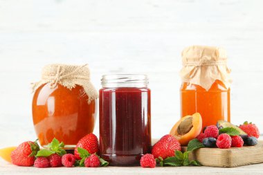 Cam kavanozlarda tatlı reçel ve beyaz arka planda olgun böğürtlen