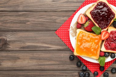 Reçelli tost ve ahşap masada taze böğürtlen