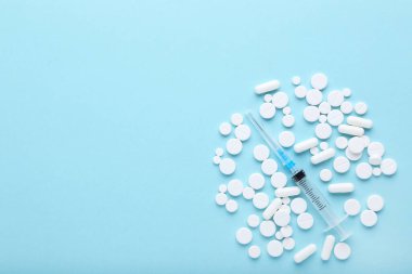 Mavi arka planda şırıngalı beyaz haplar.
