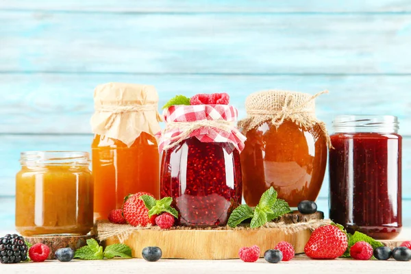 Süße Marmelade Glas Mit Reifen Beeren Auf Blauem Hintergrund — Stockfoto