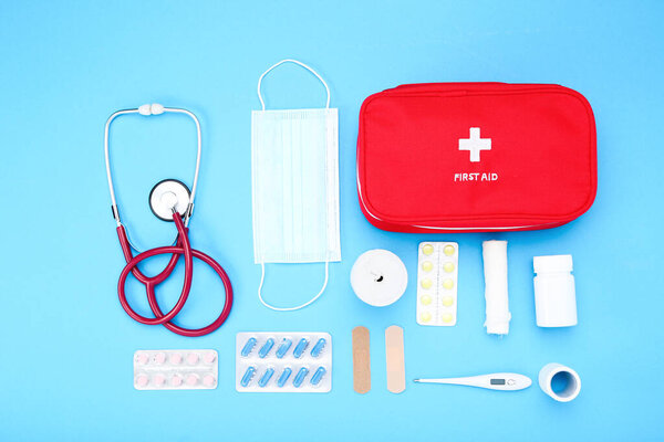 First aid kit with medical supplies on blue background