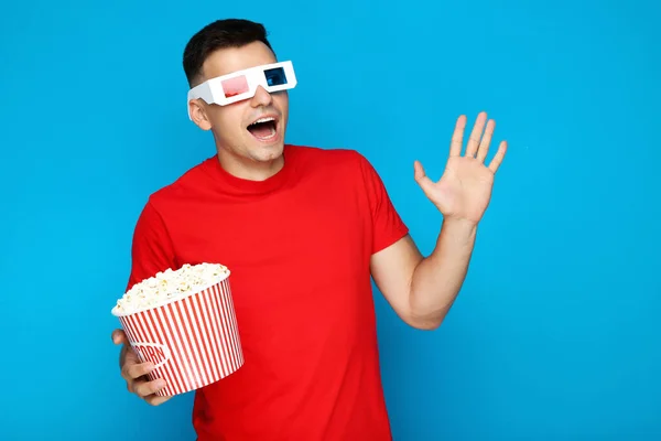 Junger Mann Mit Eimer Popcorn Und Brille Auf Blauem Hintergrund — Stockfoto