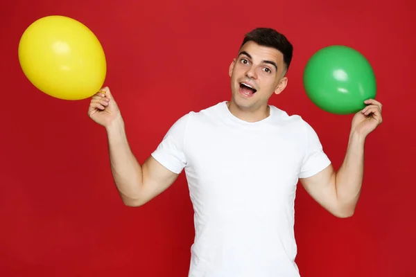 Yuong Mann Mit Luftballons Auf Rotem Hintergrund — Stockfoto