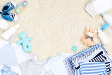 Bebek kıyafetleri ve halı üzerinde bebek bezi.