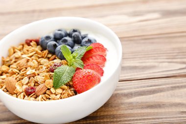 Kahverengi ahşap arka planda taze böğürtlenli lezzetli granola.