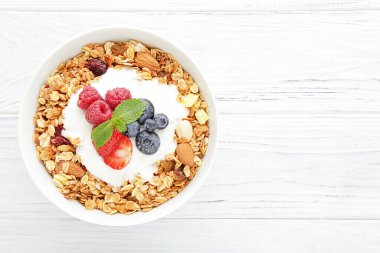 Beyaz ahşap arka planda taze böğürtlenli lezzetli granola.