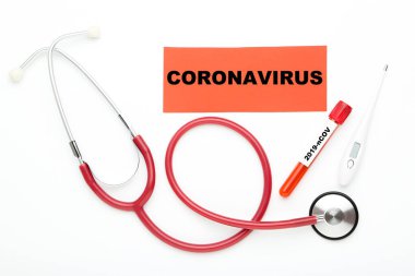 Beyaz zemin üzerinde stetoskop, termometre ve test tüpü ile Coronovirus metin