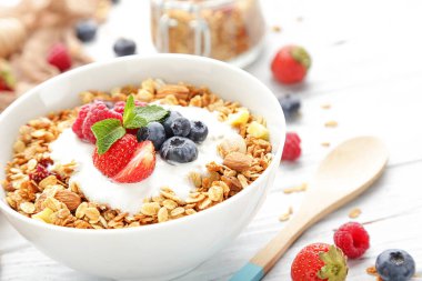 Beyaz ahşap arka planda taze böğürtlenli lezzetli granola.