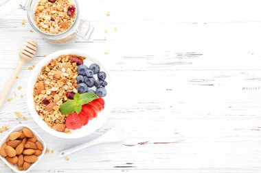 Beyaz ahşap arka planda taze böğürtlenli lezzetli granola.