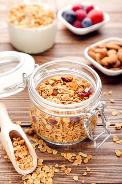 Cam kavanozda lezzetli granola ve kahverengi ahşap arka planda kepçe