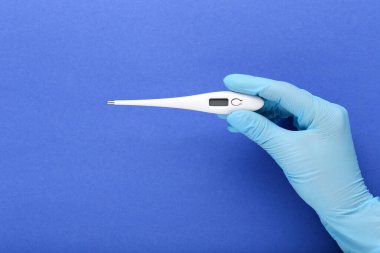 Doktor termometreyi mavi arkaplanda tutuyor