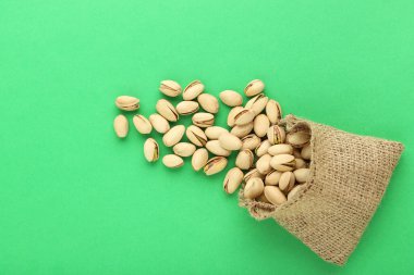 Yeşil arka planda çuval içinde lezzetli fıstıklar.