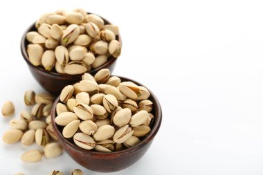 Beyaz arka planda kâselerde lezzetli fıstıklar.