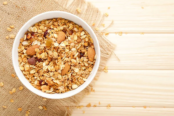 Tasty granola in bowl on brown wooden background