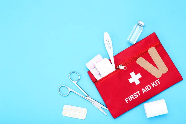 First aid kit with medical supplies on blue background