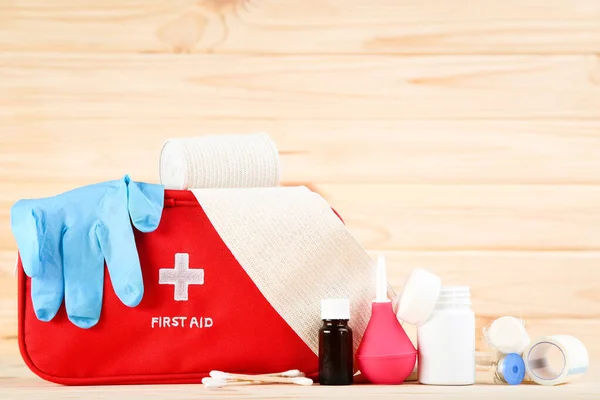 First aid kit with medical supplies on brown wooden table