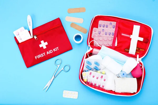 First aid kit with medical supplies on blue background