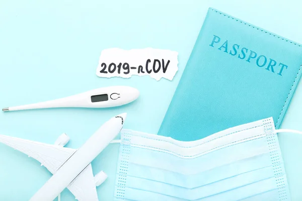 Text 2019-nCov with medicine mask, thermometer, passport and airplane model on blue background