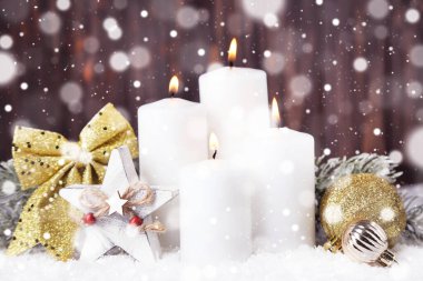 Süslü Noel mumları ve kahverengi ahşap arka planda beyaz kar.