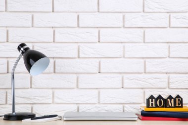 Elektrik lambalı dizüstü bilgisayar ve tuğla duvar zemininde kitaplar.