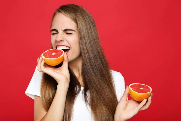 Mladá Dívka Jíst Čerstvé Grapefruit Červeném Pozadí — Stock fotografie