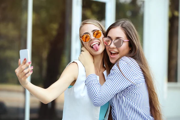 Güneş Gözlüklü Iki Genç Kız Sokakta Cep Telefonuyla Selfie Çekiyor — Stok fotoğraf