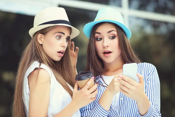 Sokakta cep telefonu kullanan iki genç kız arkadaş.