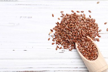 Kahverengi keten tohumları beyaz ahşap arka planda kepçe