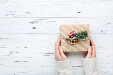 Dişi eller, tahta arka planda hediye kutusunu tutuyor.