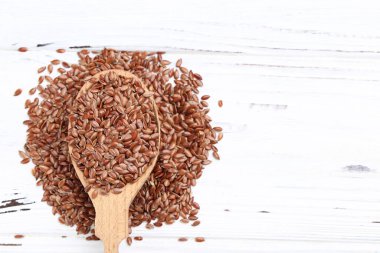 Kahverengi keten tohumları beyaz ahşap arka planda kaşık içinde