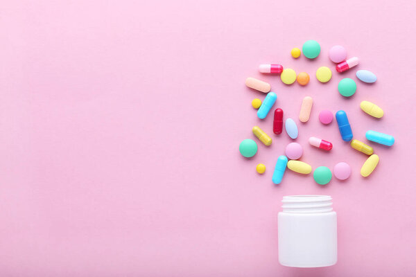 Colorful pills and bottle on pink background