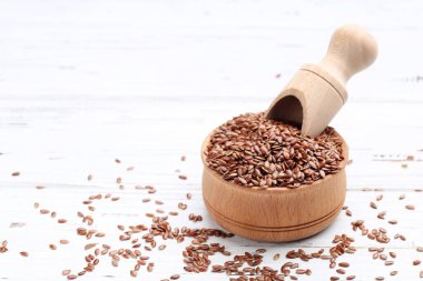 Kasede keten tohumu ve beyaz ahşap arka planda kepçe