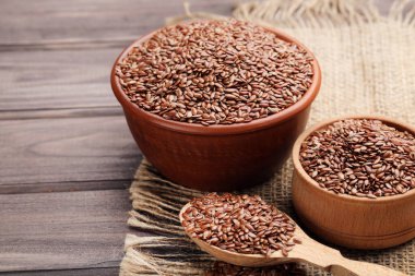 Kaselerde keten tohumu ve kahverengi ahşap arka planda kaşık.