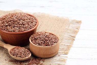 Kaselerde keten tohumu ve beyaz ahşap arka planda kaşık.