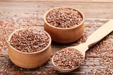 Kaselerde keten tohumu ve kahverengi ahşap arka planda kaşık.