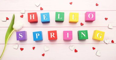 White tulip flower with with text Hello Spring on wooden cubes and small hearts