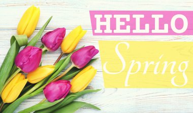 Bouquet of tulips with text Hello Spring on wooden table