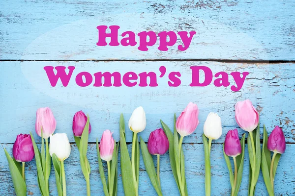 蓝色木制桌子上的郁金香花束 上面印有 快乐的妇女日 — 图库照片